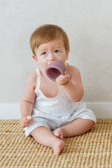 Baby sitting on woven mat drinking from a cup in Avauma Butter Daisy tank top set
