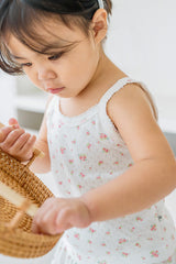 Close-up of baby girl holding basket in Avauma rose belle picnic floral tank top

