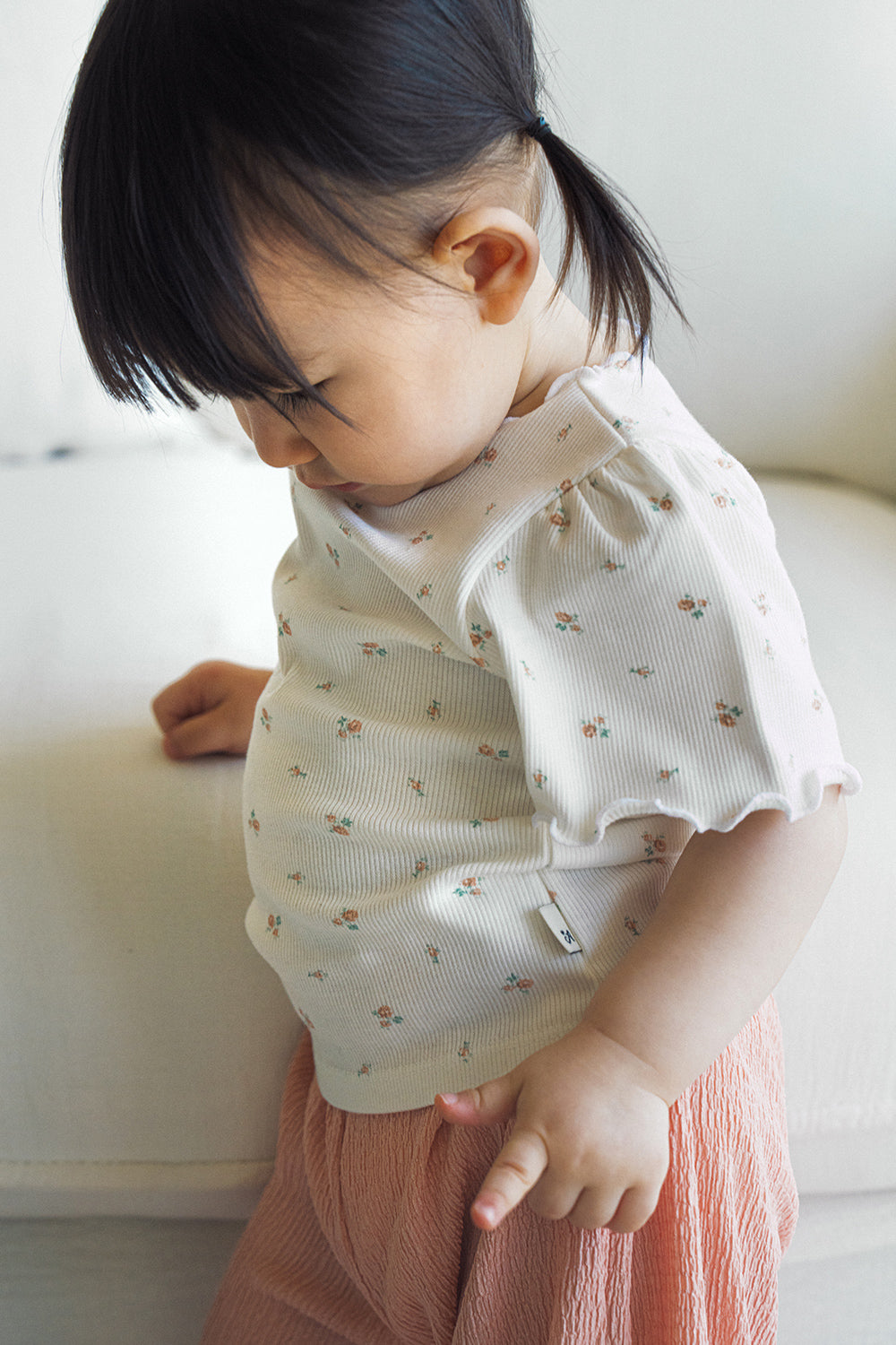 Close-up of a toddler wearing the Avauma cream floral puff-sleeve top and pink wide-leg ribbed pants.
