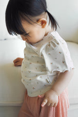 Close-up of a toddler wearing the Avauma cream floral puff-sleeve top and pink wide-leg ribbed pants.