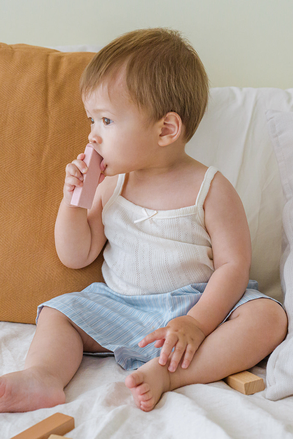 Toddler sitting in Avauma Sunny Stripe Pants Blueberry Powder. Child playing with blocks, wearing light blue striped shorts and a white top.

