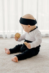 Baby sitting and playing while wearing Avauma's Coco Classic Long Sleeve Set in Black Moon color - soft and breathable baby sleepwear for all-day comfort.