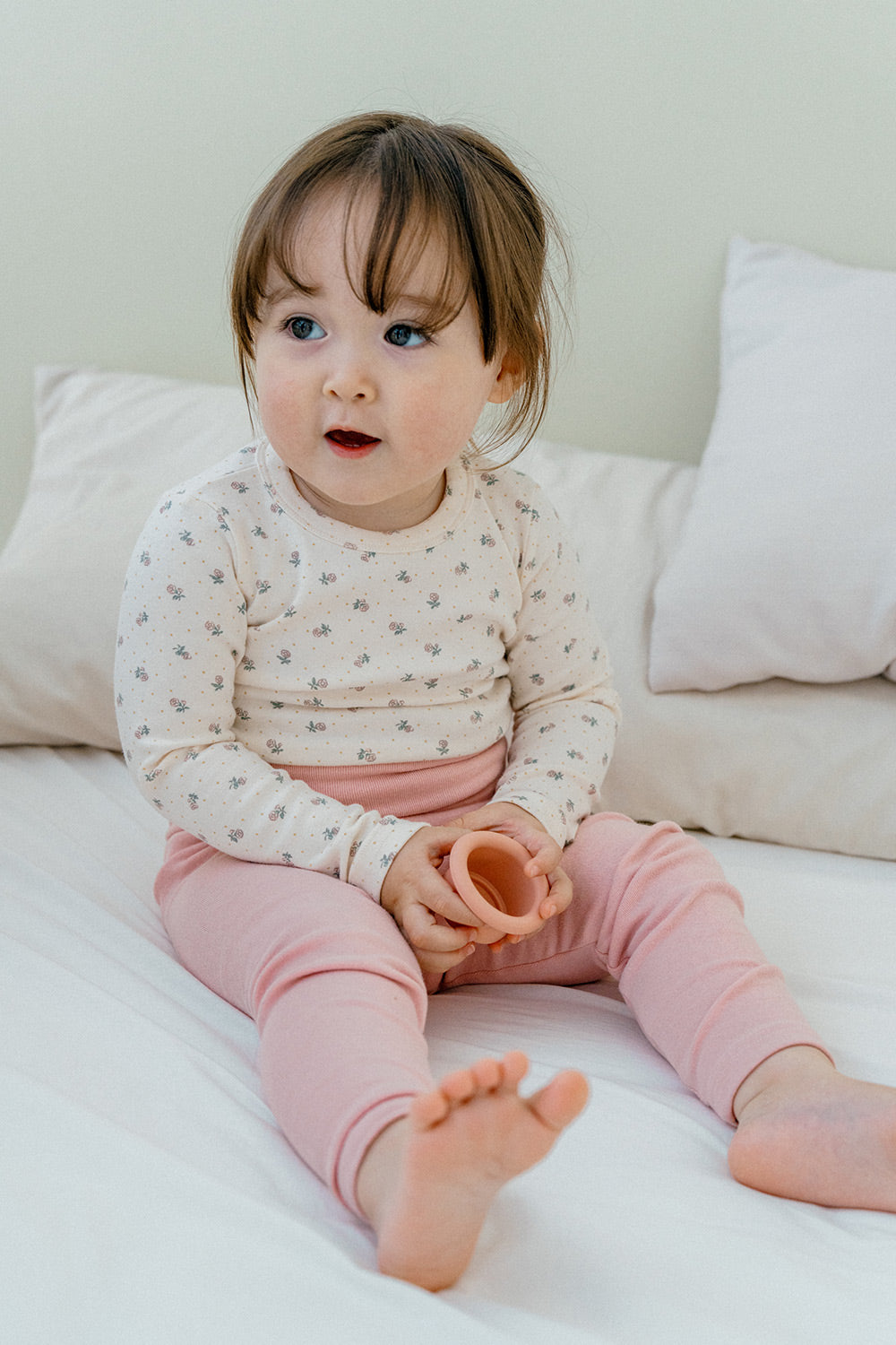 Toddler sitting on a bed in Avauma Lovely Duet Setup Blossom Strawberry, cozy baby outfit with a floral top and pink pants.