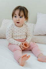 Toddler sitting on a bed in Avauma Lovely Duet Setup Blossom Strawberry, cozy baby outfit with a floral top and pink pants.