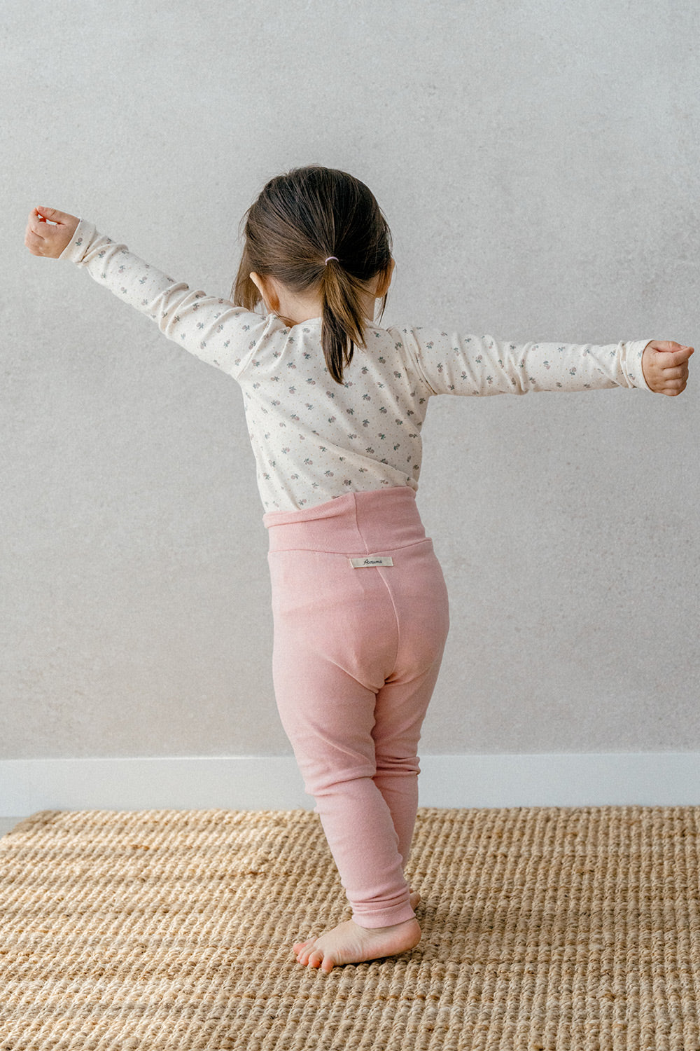 Back view of a toddler in Avauma Lovely Duet Setup Blossom Strawberry, highlighting the pink high-waisted pants and floral top.