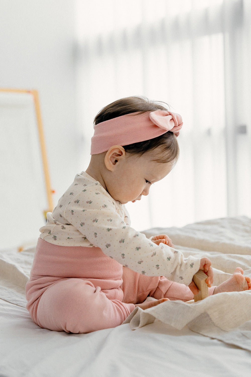 A baby wearing the Avauma Lovely Duet Setup - Blossom Strawberry, featuring a floral-patterned long sleeve top paired with pink high-waisted pants, perfect for cozy days at home.