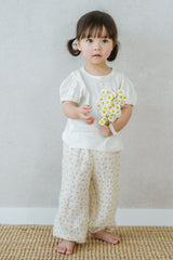  Girl wearing Avauma Breeze Jogger Pants in yellow flower print, standing barefoot on woven mat.
