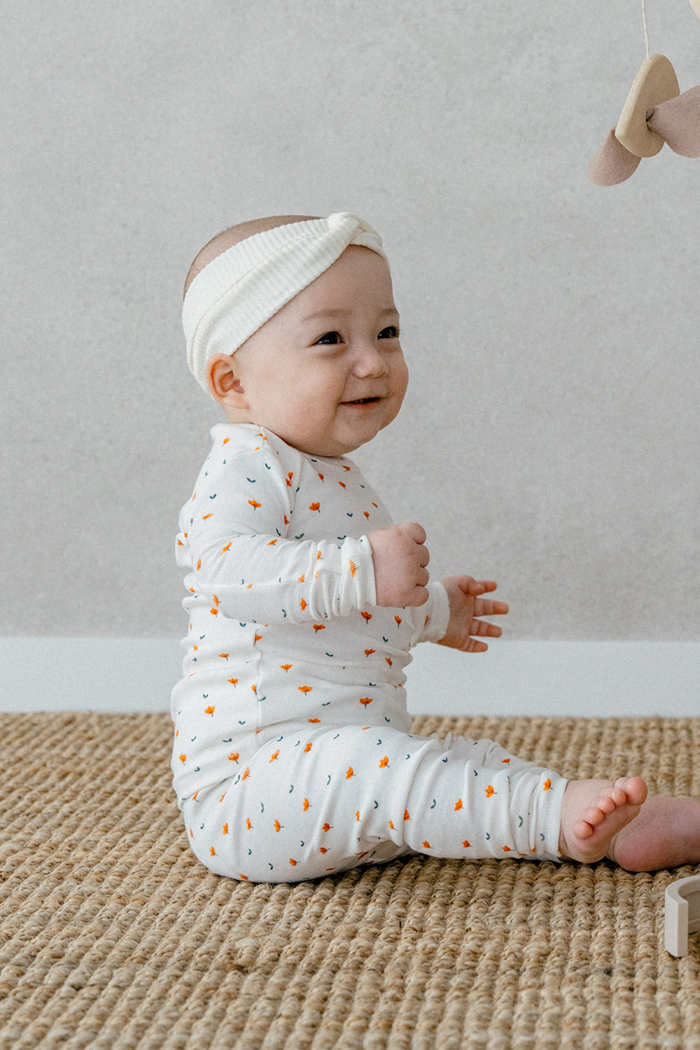 Baby dressed in Avauma Mini Fleur Long Sleeve Set - Floral Africot, showcasing the vibrant orange flower patterns on a soft and cozy fabric.