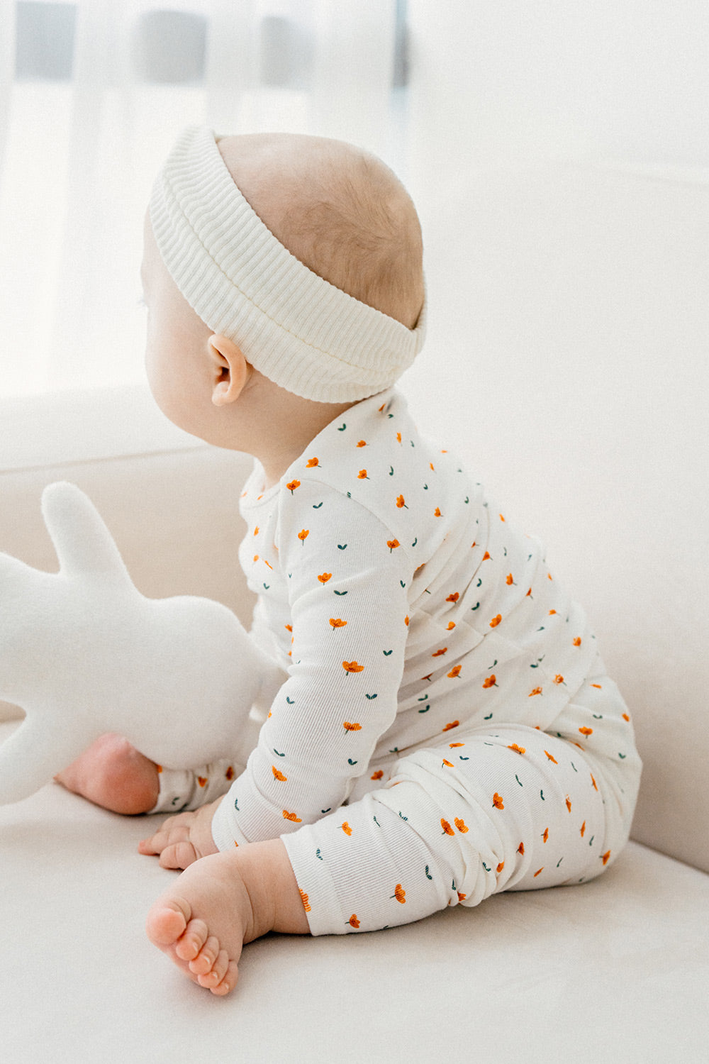 Side view of a baby in Avauma Mini Fleur Long Sleeve Set - Floral Africot, featuring playful orange floral accents perfect for everyday wear.