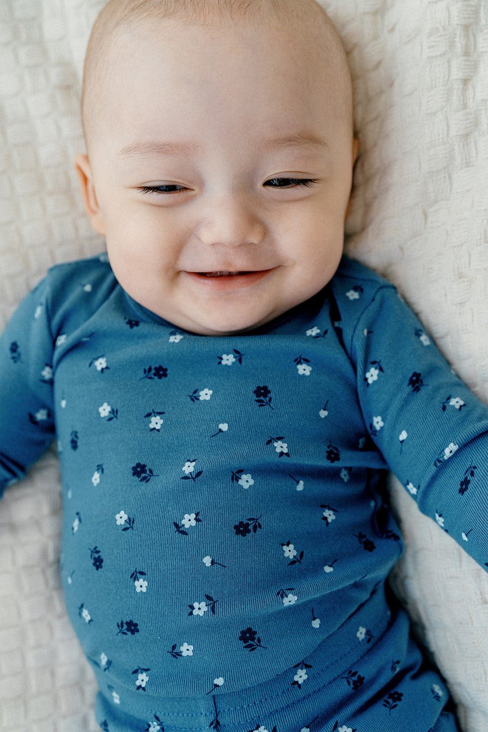 Close-up of a smiling baby in Avauma Mini Fleur Long Sleeve Set - Floral Navy, featuring a playful and cozy pajama set with charming floral patterns.