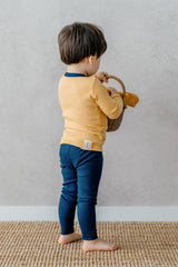 "Back view of a toddler wearing Avauma's Coco Classic Long Sleeve Set in Mango Marine color - cozy yellow and navy baby pajamas, perfect for sleepwear and playtime.