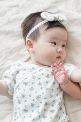 Newborn baby lying down wearing Avauma Petite Garden Headband in Sky Garden, matching floral outfit