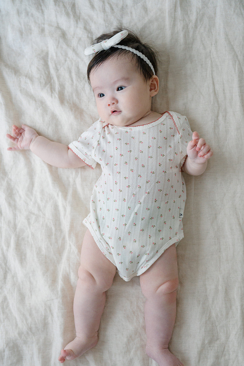 Baby Lying Down in Avauma Petite Garden Rosegarden Short Sleeve Ribbed Bodysuit, Pink Flower Pattern

