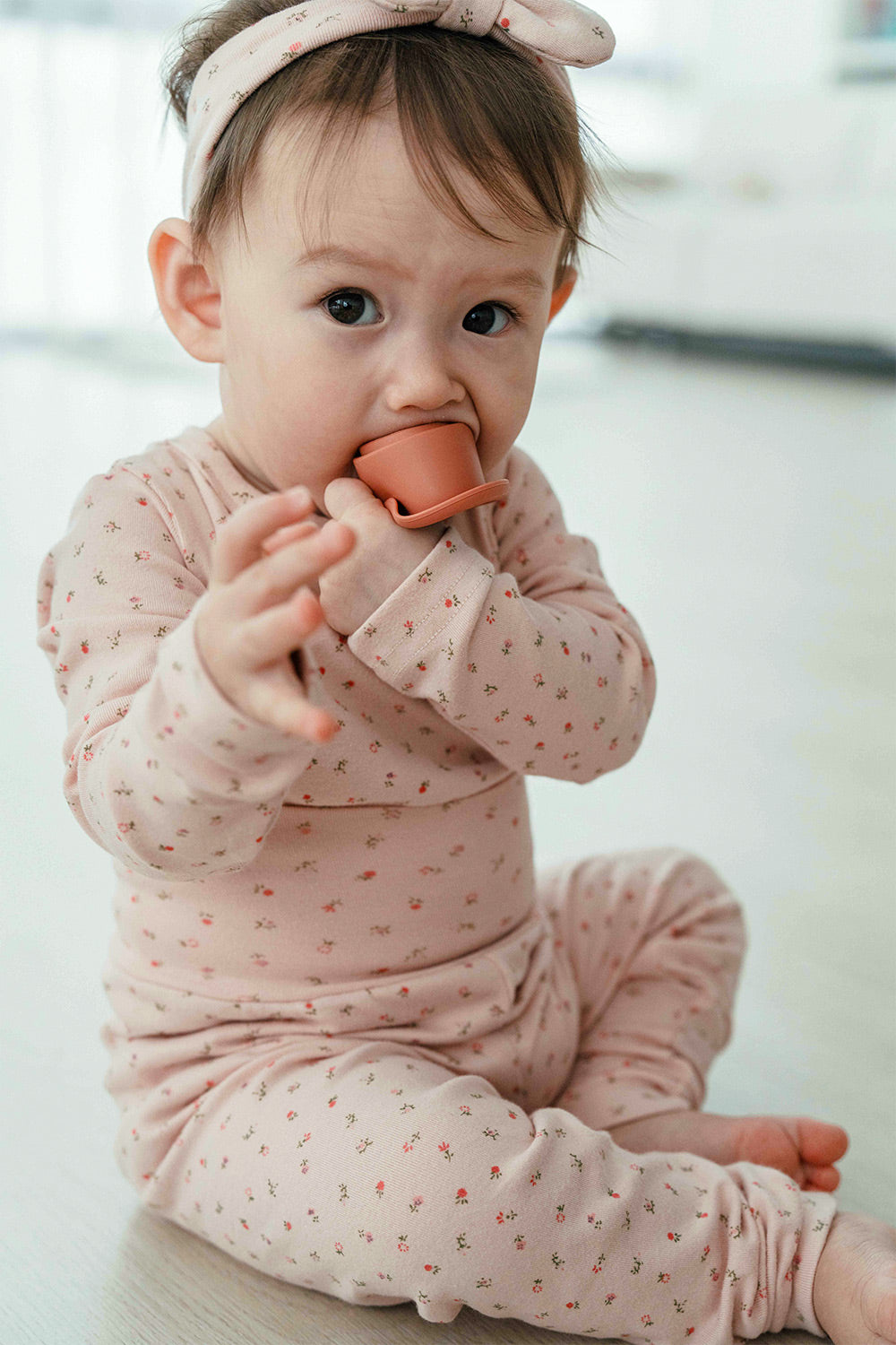 Toddler girl sitting in Avauma Floral Melody Long Sleeve Baby Pajamas - Powder Pink, a comfortable floral print pajama set for baby girls.