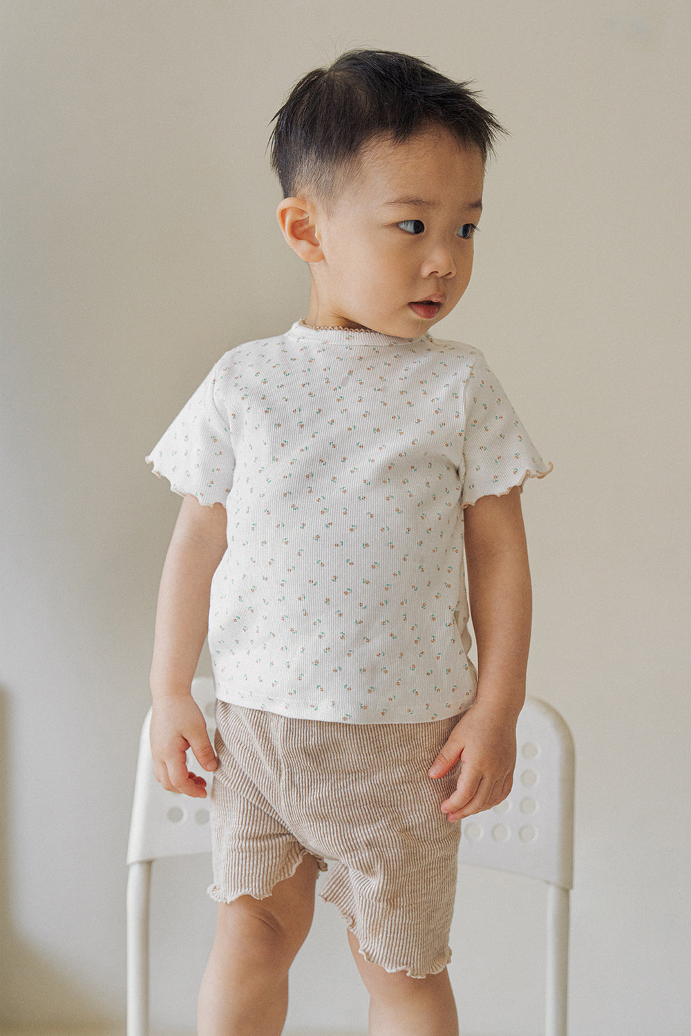 Front view of a young boy wearing Avauma floral patterned baby summer setup in honey beige.
