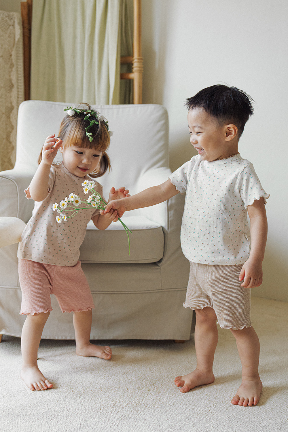 Two toddlers playing together in Avauma floral baby outfits, honey beige and dusty pink colors.