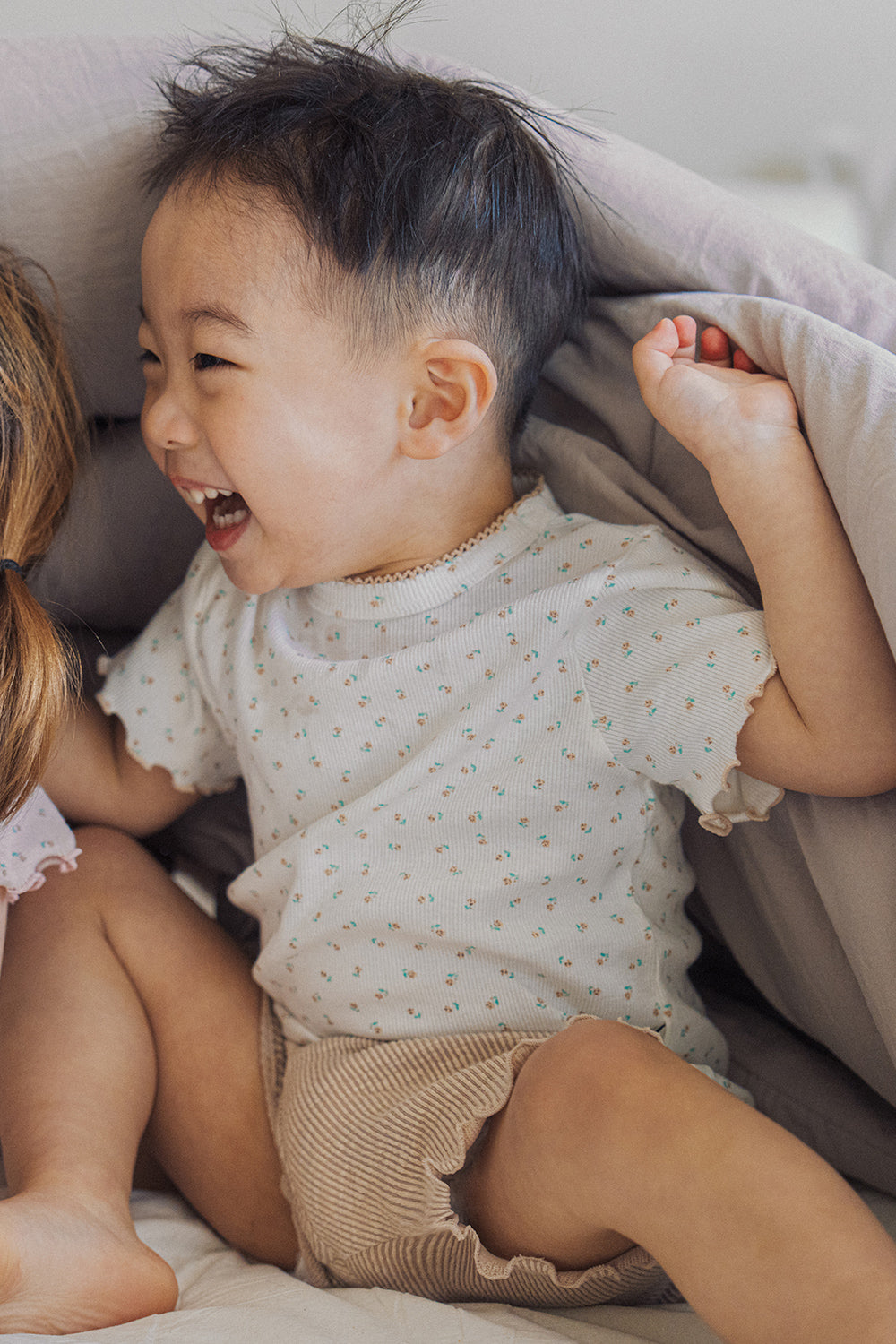 Close-up of a laughing boy in Avauma floral t-shirt, highlighting the soft scalloped edges.