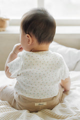 Rear view of a baby showing the Avauma brand logo label on the honey beige ribbed shorts.