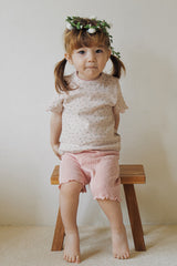 A girl with a flower crown sitting on a wooden stool in Avauma rosy blush baby summer setup.