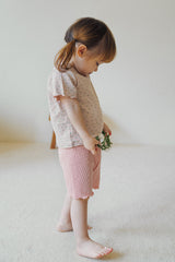 Side view of a toddler wearing Avauma floral patterned baby clothes in soft rosy blush color.