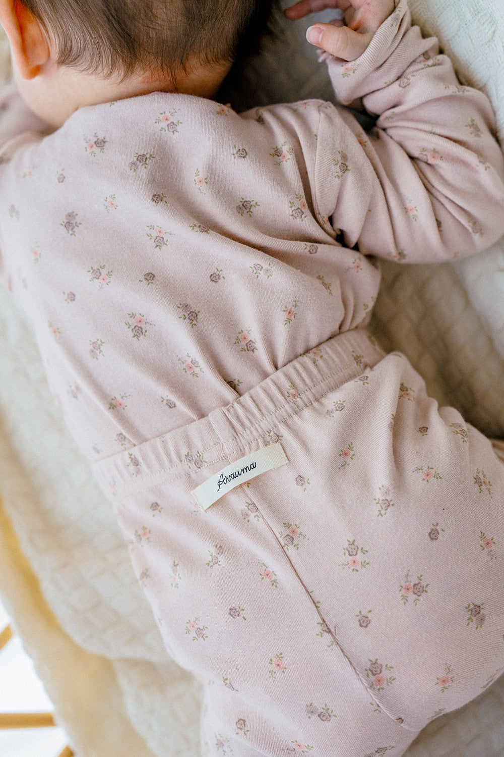 Back view of a baby in Avauma Fluid Blossom Long Sleeve Baby Pajamas - Strawberry Milk, focusing on the floral print and soft fabric of the pink pajama set, perfect for toddlers.