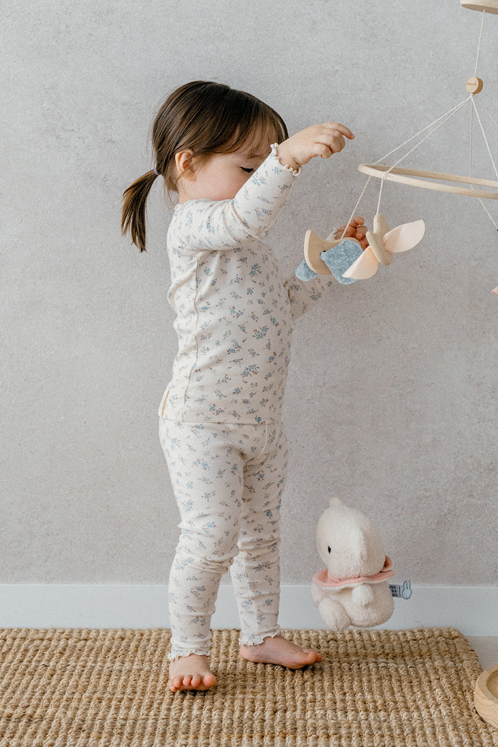 Back view of a toddler wearing Avauma Fluid Blossom Long Sleeve Set - Vanilla Flower, highlighting the floral design and frill details of the comfortable baby pajama set.